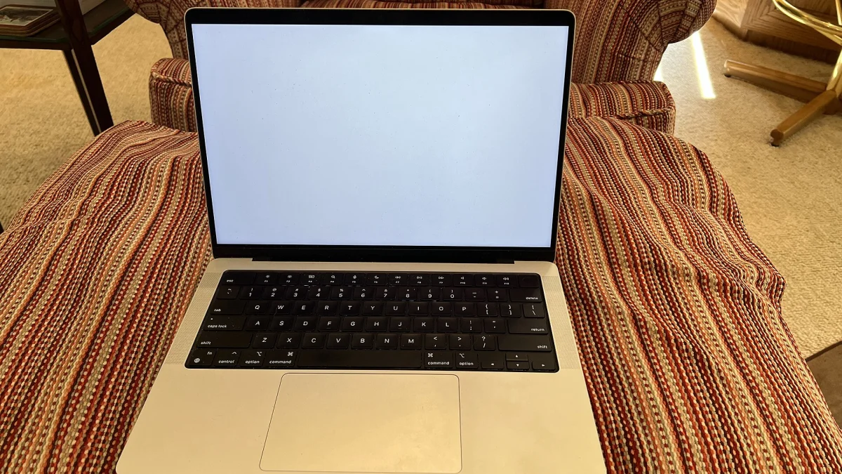 Un MacBook Pro 14 pouces argent ouvert, posé sur un fauteuil