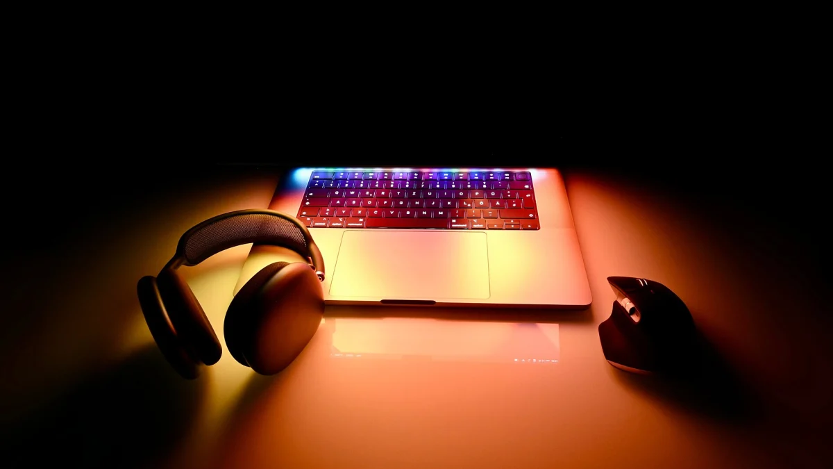 Un MacBook Pro 16 pouces ouvert sur un bureau sombre, entre un casque et une souris