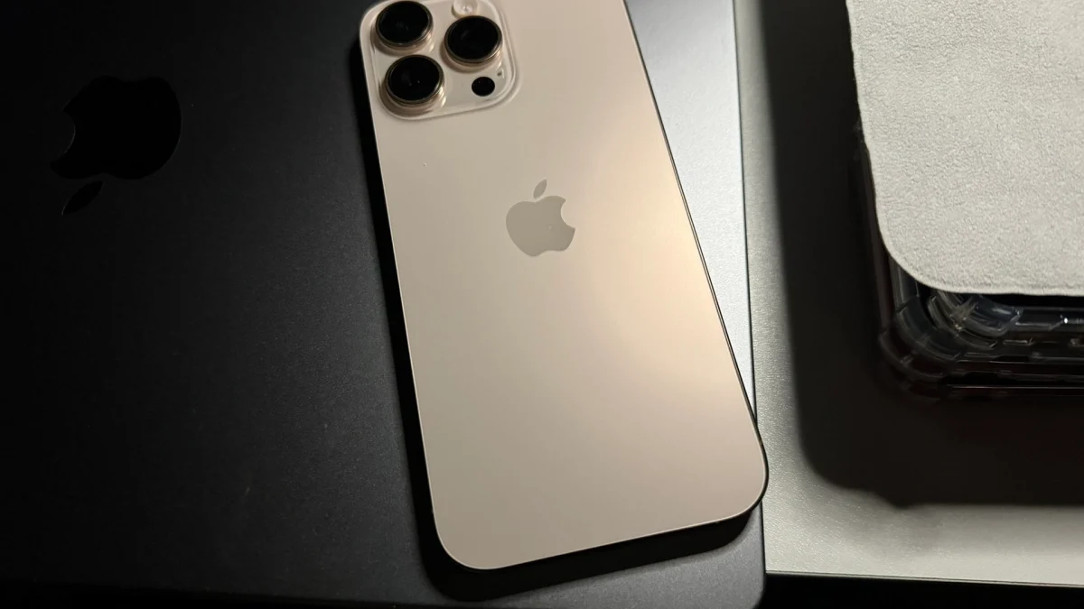 Le dos d’un iPhone 16 Pro Max titane sable posé sur une surface sombre